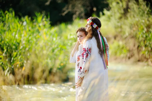 Две девушки в украинских футболках на фоне реки — стоковое фото
