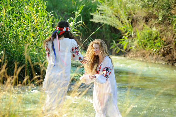 two girls in the Ukrainian national clothes swimming in the rive
