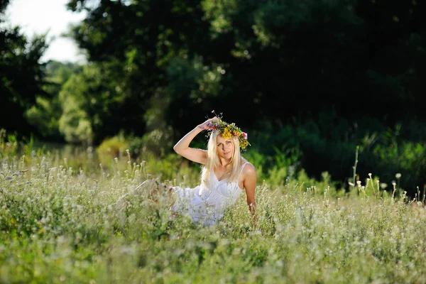 Lány a fehér sundress és rá fej üljön a virágok koszorút — Stock Fotó