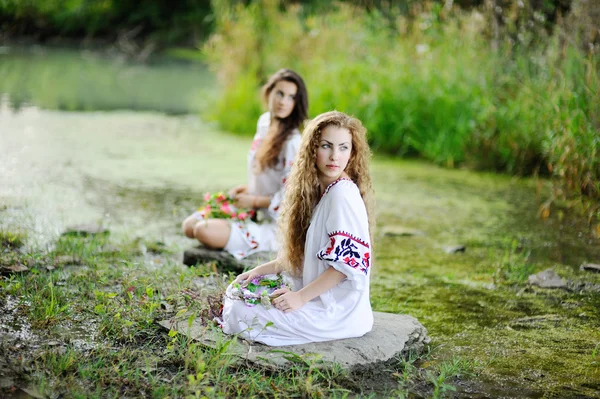 Deux filles en chemises ukrainiennes sont sur le fond de la rivière — Photo