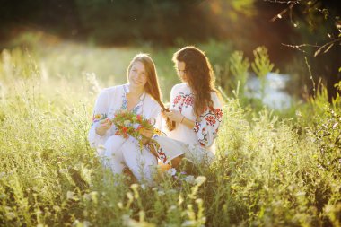 iki kız Ukrayna Ulusal çim üzerinde oturan elbise. Kız