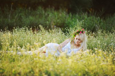 kız beyaz bir sundress ve onun baş sit üzerinde çiçek çelenk