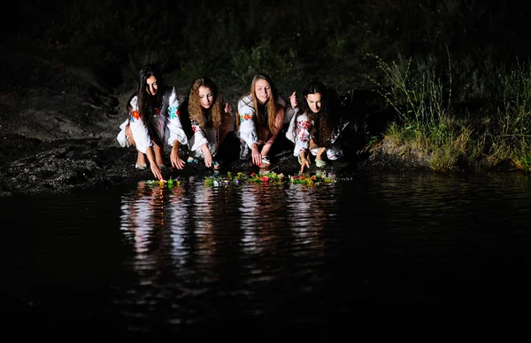 Ukrainska flickor i skjortor tillåtna kransar av blommor på vattnet — Stockfoto