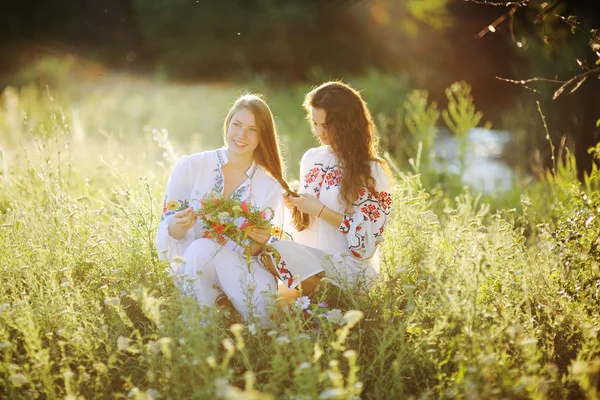 Dos niñas en vestido nacional ucraniano sentado en la hierba. Chica. Imagen De Stock