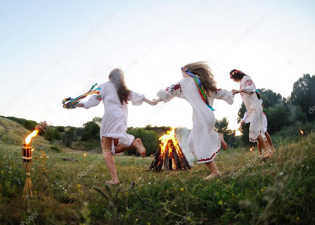 Girls in Ukrainian national shirts dancing around a campfire