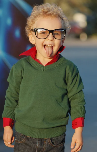 Curly-haired boy with glasses showing tongue — Stock Photo, Image