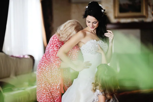 Мама и маленькая девочка помочь невесте носить свадебное платье. утро — стоковое фото