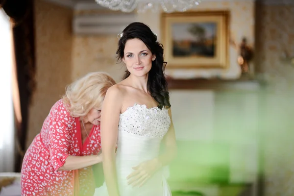 Мама и маленькая девочка помочь невесте носить свадебное платье. утренняя невеста — стоковое фото