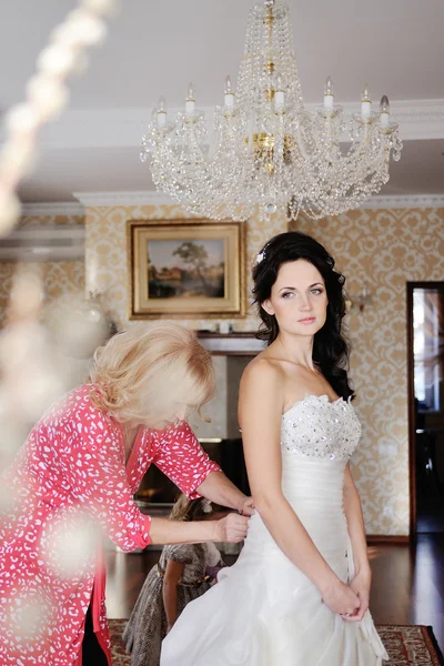 Мама помогает невесте надеть свадебное платье. утренняя невеста — стоковое фото