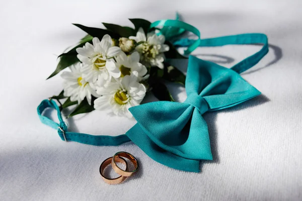 Anillos de boda y una mariposa corbata azul sobre un fondo de blanco — Foto de Stock