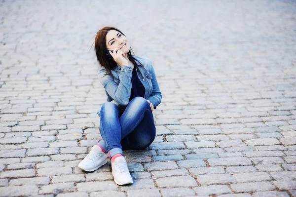 Giovane ragazza seduta in strada e parlare sul cellulare — Foto Stock