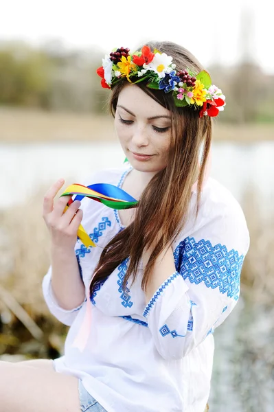 Ukrainische Mädchen in einem Hemd und einem Blumenkranz auf dem Kopf auf einem b — Stockfoto