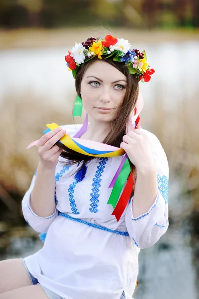 Ukrainische Mädchen in einem Hemd und einem Blumenkranz auf dem Kopf auf einem b — Stockfoto