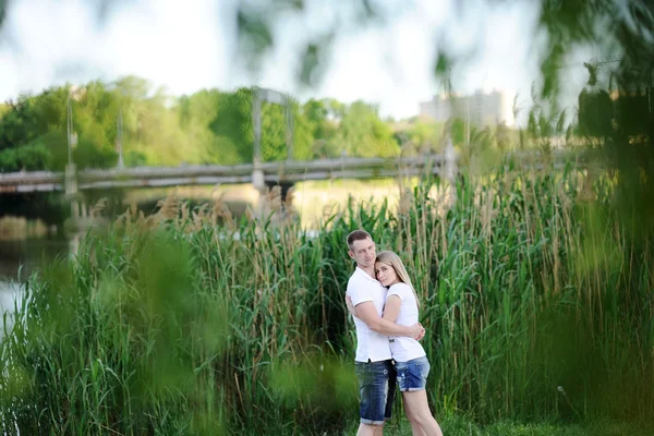 Chico abraza a la chica sobre un fondo de árboles verdes —  Fotos de Stock