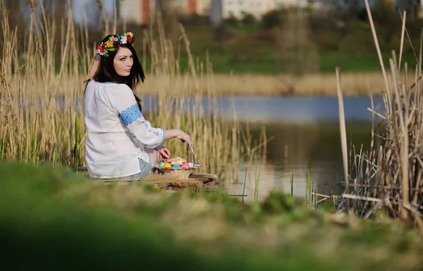 Slavische meisje in Oekraïense shirt zittend op de brug met Pasen — Stockfoto