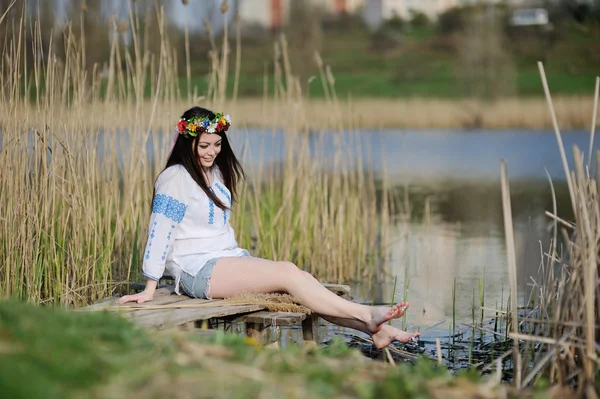 Dziewczyna moczy nogi w rzece. dziewczyna siedzi na moście w U — Zdjęcie stockowe