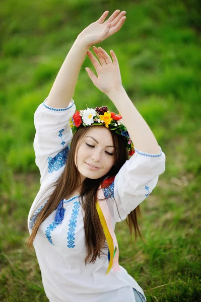 Украинка в рубашке и с цветочным венком на голове тянет — стоковое фото