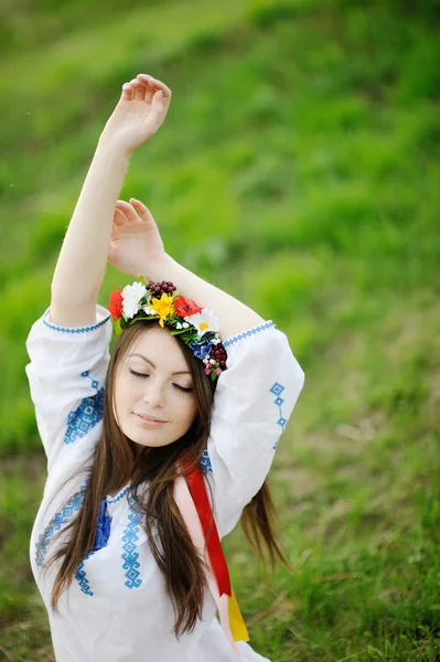 Украинка в рубашке и с цветочным венком на голове тянет — стоковое фото
