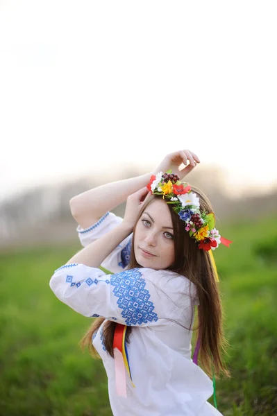 Ukrainian girl in a shirt and a floral wreath on her head pullin — Stock Photo, Image