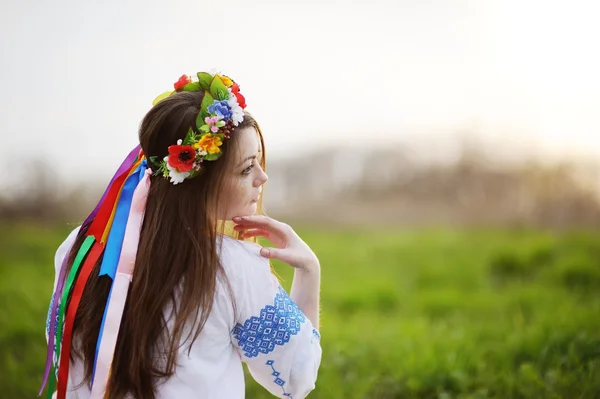 Ukrainische Mädchen in einem Hemd und einem Blumenkranz auf dem Kopf auf einem b — Stockfoto