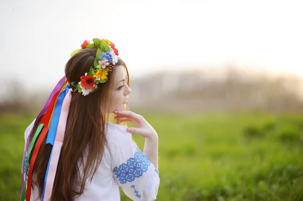 Menina ucraniana em uma camisa e uma coroa de flores em sua cabeça em um b — Fotografia de Stock