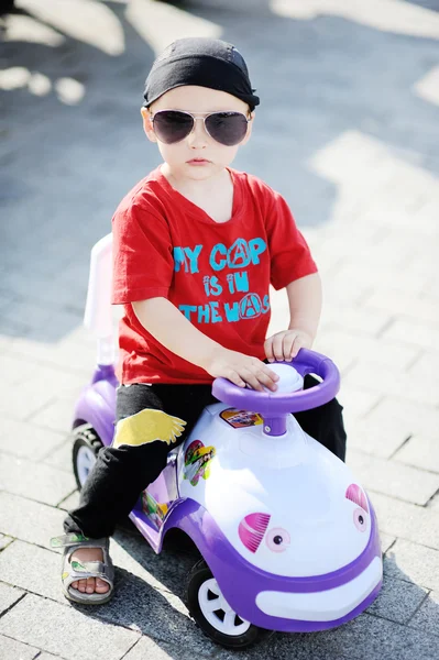 Junge mit Sonnenbrille am Steuer eines Spielzeugautos — Stockfoto