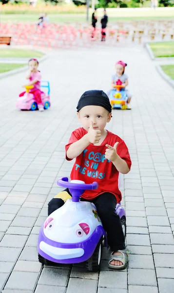 Bebé niño conducir un coche de juguete sosteniendo pulgares hacia arriba —  Fotos de Stock