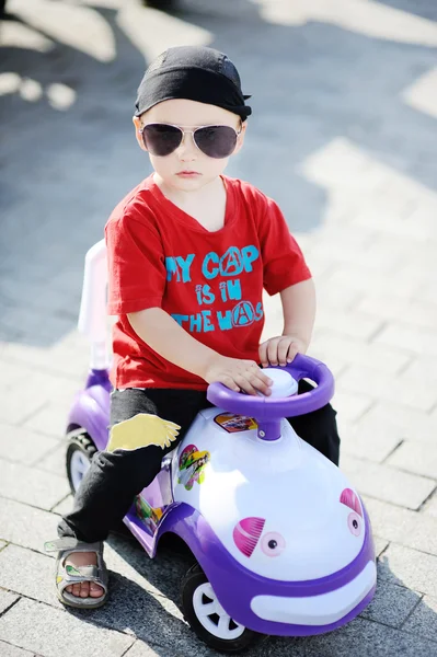 Junge mit Sonnenbrille am Steuer eines Spielzeugautos — Stockfoto