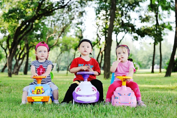 Kleiner Junge und zwei kleine Mädchen fahren Spielzeugautos — Stockfoto