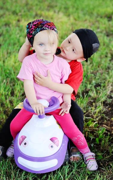 Kleine Jungen und Mädchen am Steuer eines Spielzeugautos. Junge umarmt Mädchen — Stockfoto