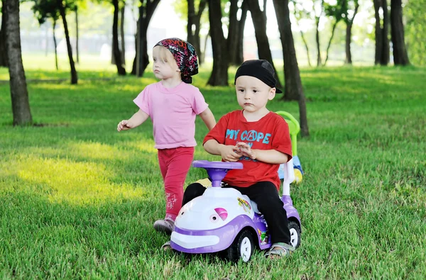 Little boy and girl on a toy car — Stok fotoğraf