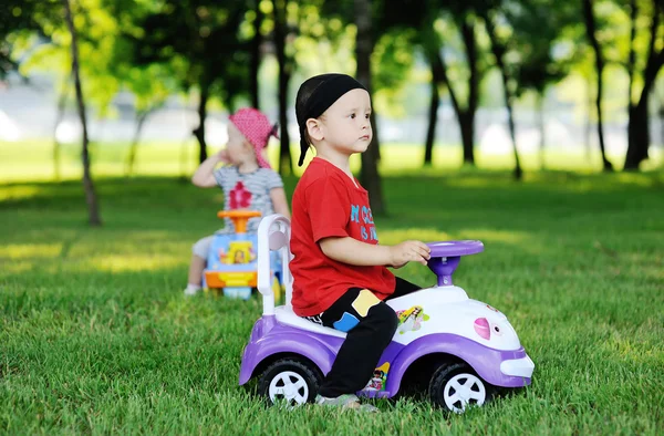 Little boy and girl on a toy car — Stock fotografie