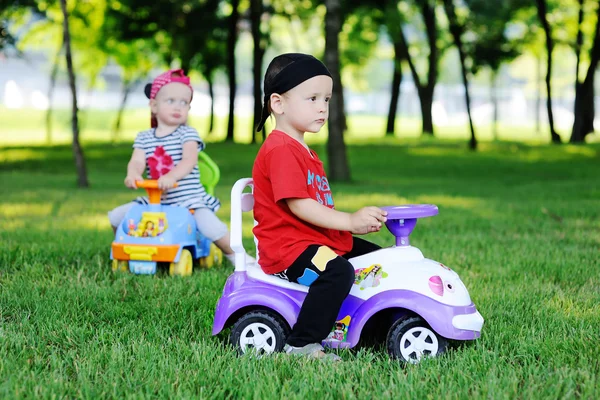 Little boy and girl on a toy car — Stok fotoğraf