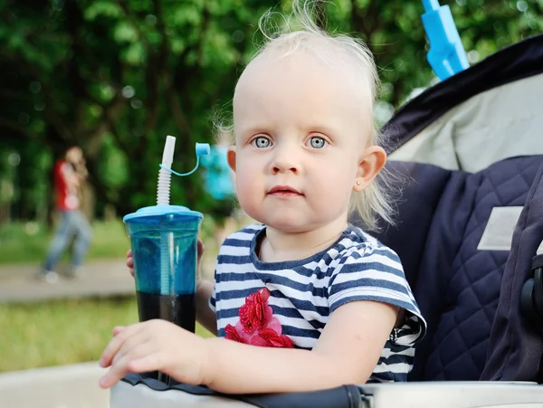 Baby sitzt im Rollstuhl und hält ein Glas Wasser — Stockfoto