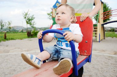 Mom and baby son play in the playground