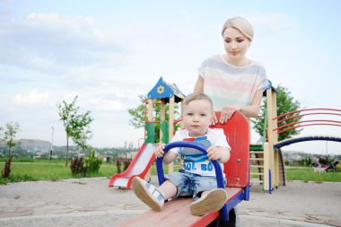 Mom and baby son play in the playground