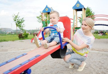 Mom and baby son play in the playground