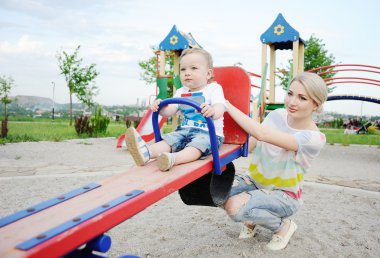 Mom and baby son play in the playground
