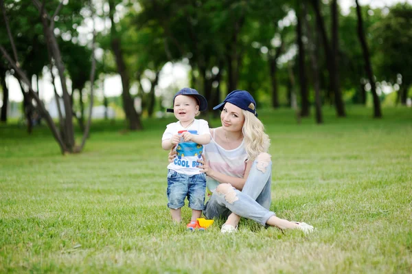 Mamá e hijo bebé en la tapa sobre un fondo de hierba verde — Foto de Stock