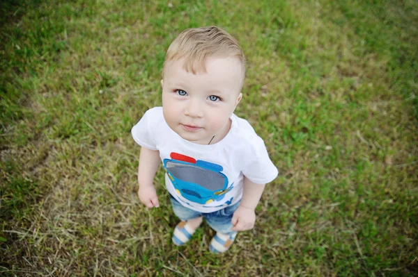 Bebé niño con ojos azules sobre un fondo de hierba verde — Foto de Stock