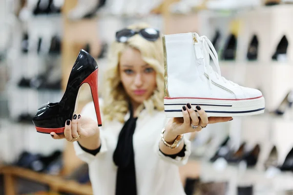Menina bonita escolhe sapatos. menina loira mede as botas na loja — Fotografia de Stock