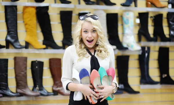 Beautiful girl chooses shoes. blonde girl measures the boots in the store — Stock Photo, Image