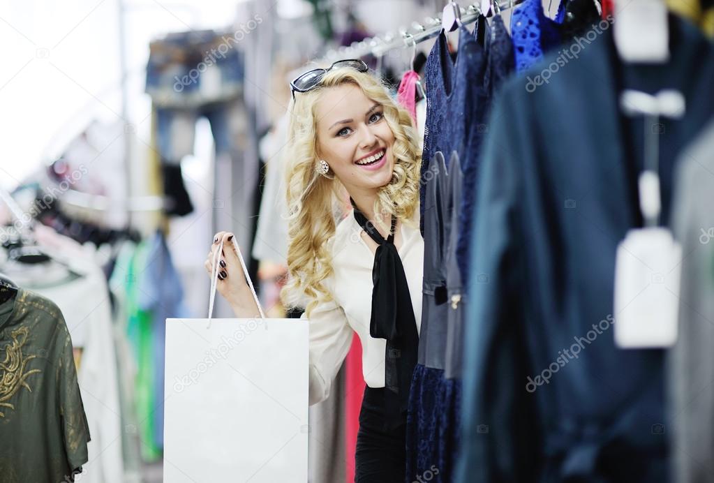 Beautiful blonde girl chooses clothes. Girl holding shopping bags.