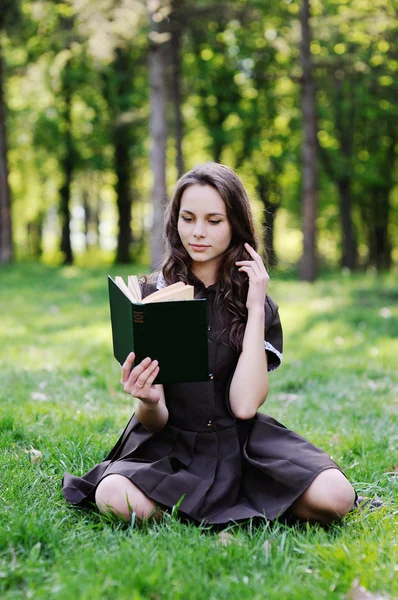 Μαθήτρια διαβάζοντας ένα βιβλίο που κάθεται στο γρασίδι. Όμορφη κοπέλα, διαβάζοντας ένα βιβλίο — Φωτογραφία Αρχείου