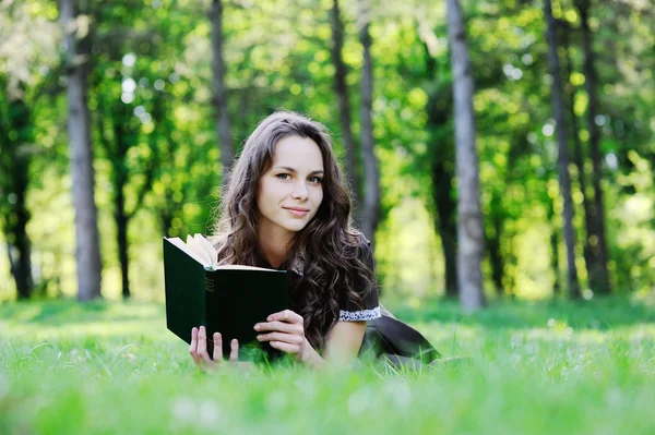 Kız öğrenci çimlere oturup kitap okumak. Güzel kız bir kitap okuma — Stok fotoğraf