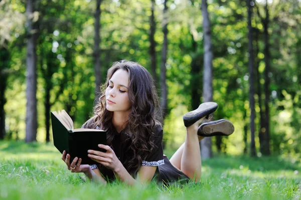 Kız öğrenci çimlere oturup kitap okumak. Güzel kız bir kitap okuma — Stok fotoğraf
