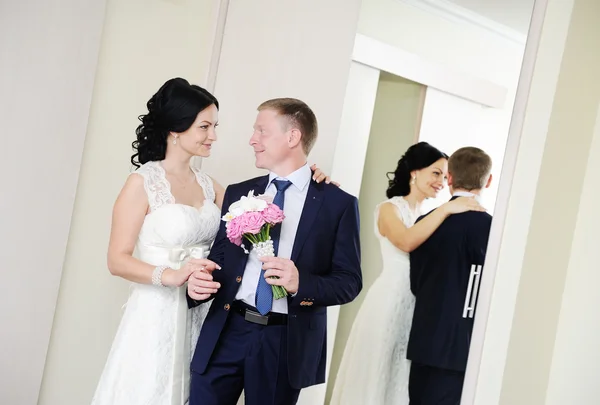 Noiva e noivo em pé na frente de um espelho — Fotografia de Stock