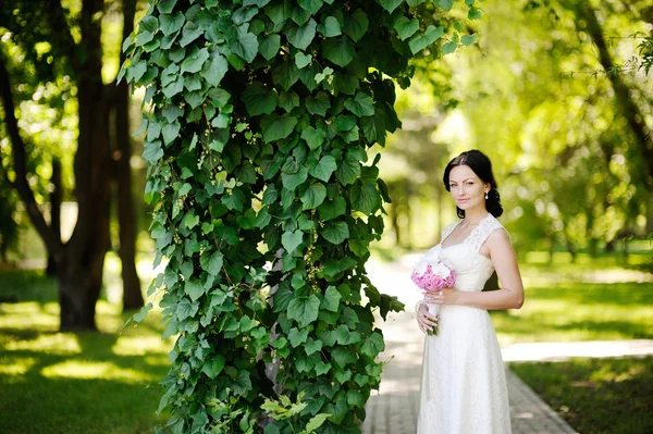 Красивая невеста со свадебным букетом на фоне зеленого — стоковое фото