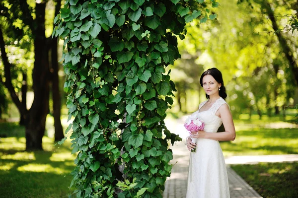 Красивая невеста со свадебным букетом на фоне зеленого — стоковое фото