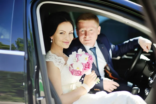The bride and groom in a wedding car — Stock Photo, Image